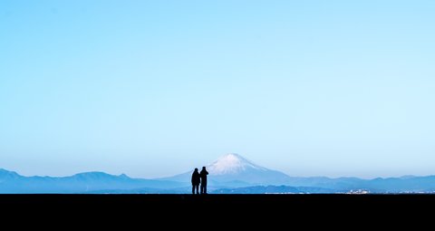 快晴の富士山を背景に寄り添うカップルのシルエット